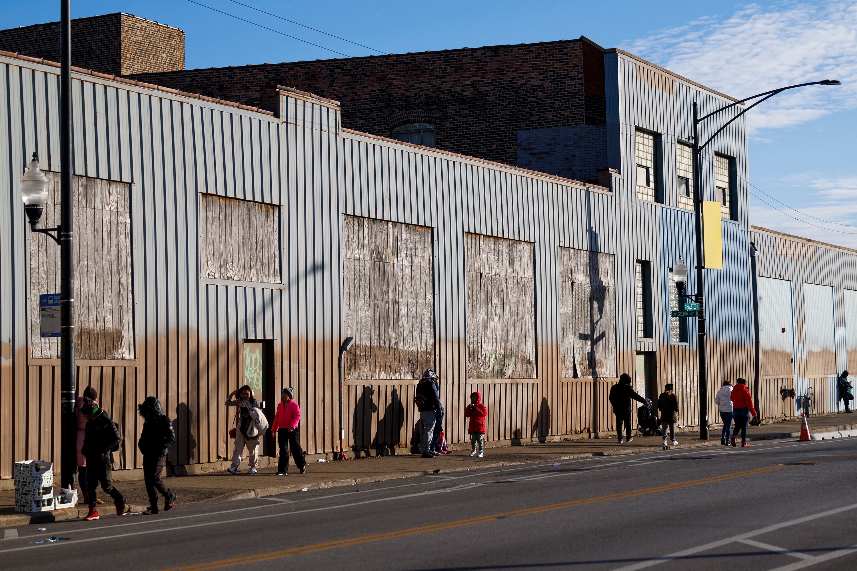Migrants walk in front of a shelter on South Halsted Street, the largest in Chicago, Illinois, in April 2024.