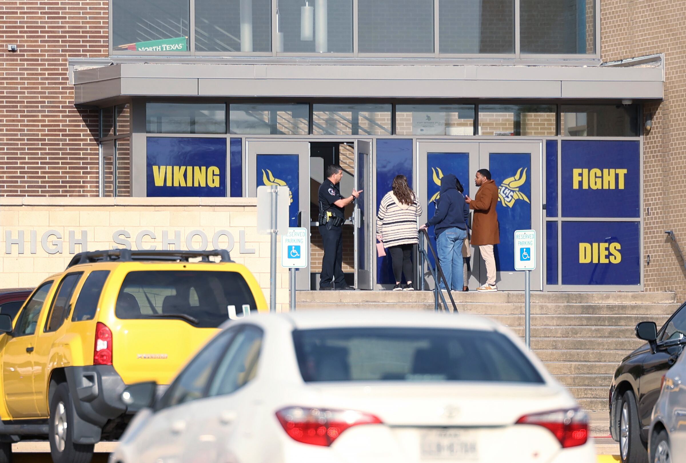 An Arlington police officer speaks to individuals outside of Lamar High School in Arlington during a lockdown after a shooting on March 20, 2023.