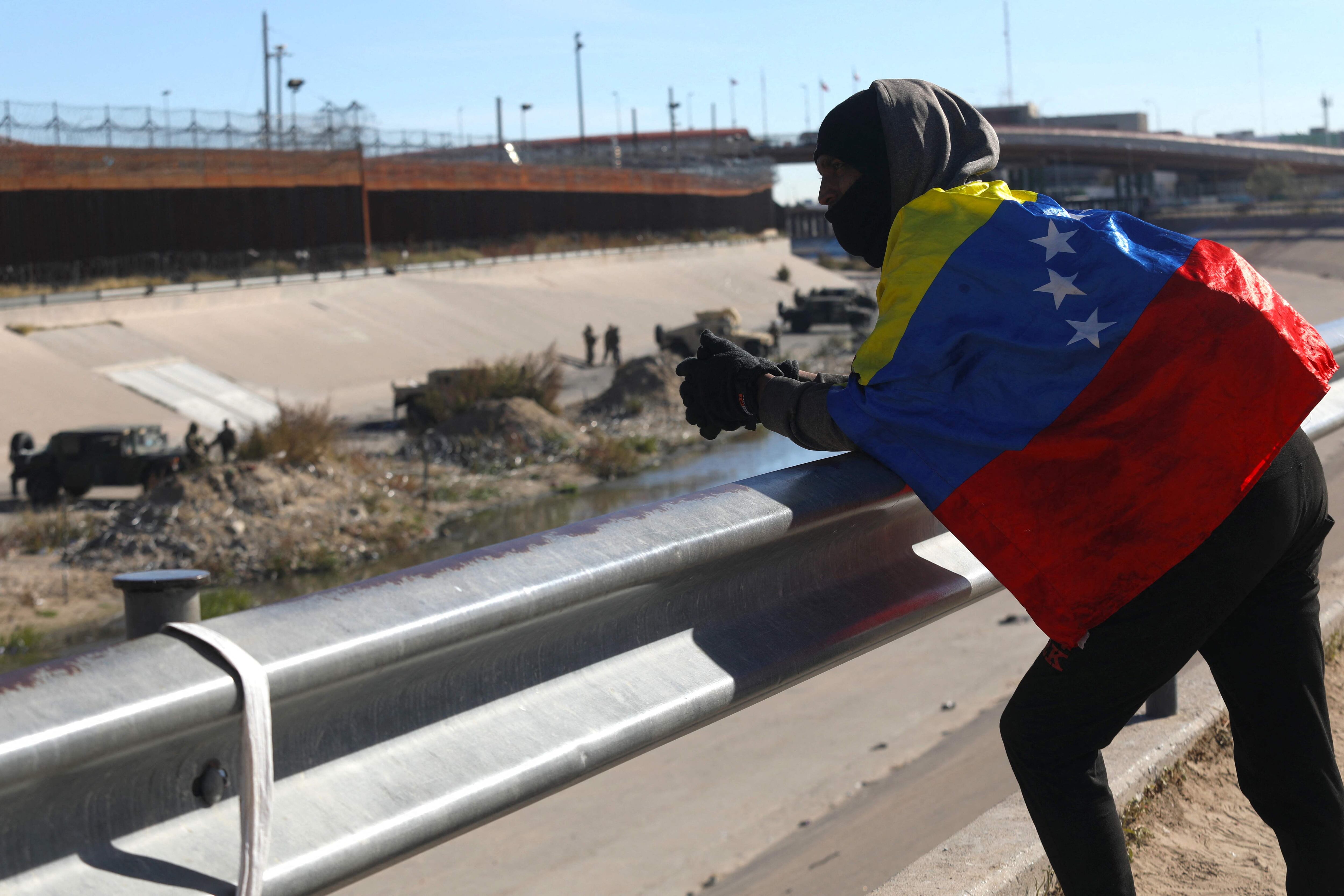 A Venezuelan migrant looks towards the United States wrapped in his country's flag as he waits for the opportunity to cross from Ciudad Juárez, Chihuahua state, Mexico, in December 2022.