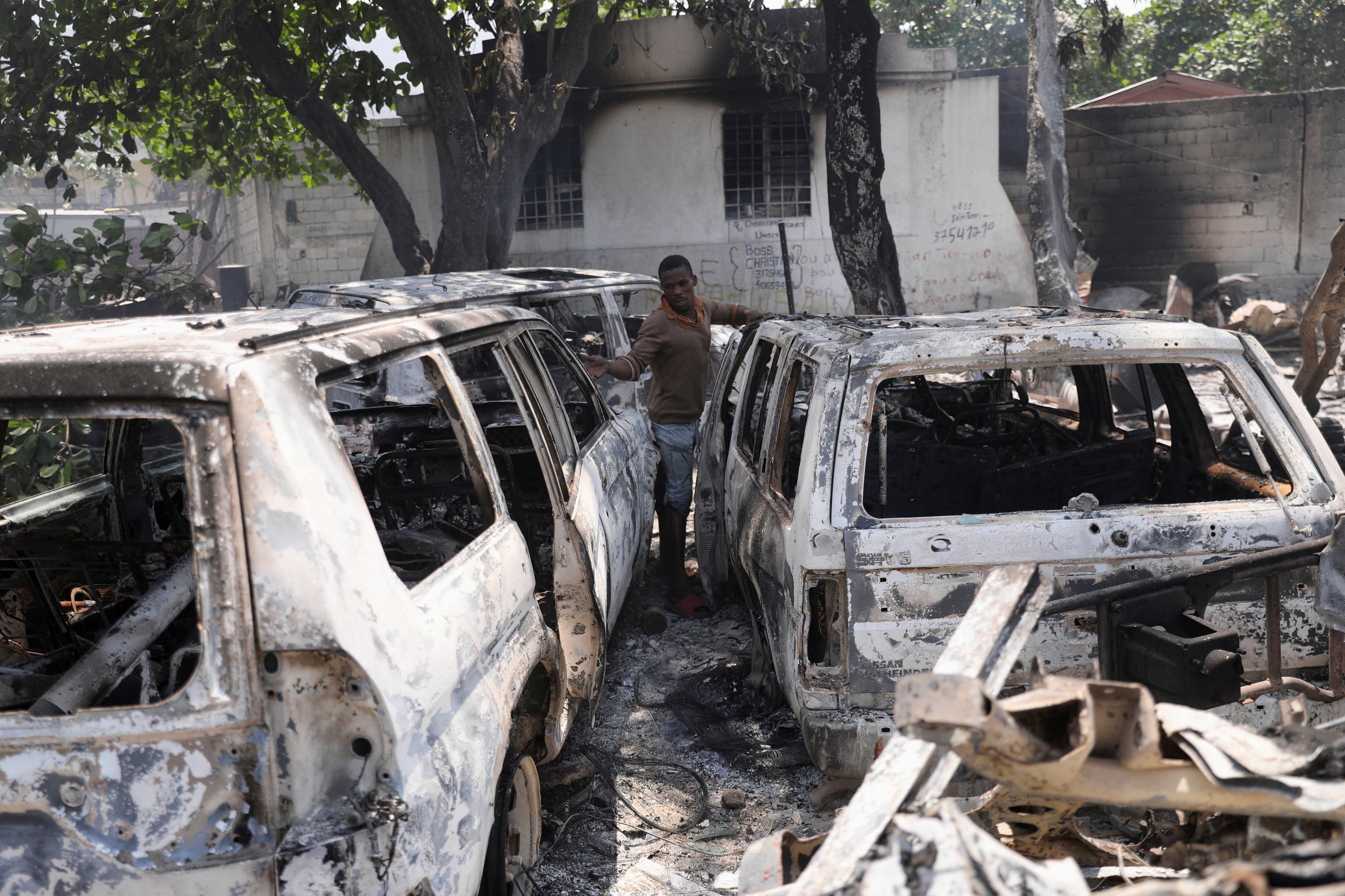 A man looks at the charred remains of vehicles near the presidential palace, after they were set on fire by gangs, in Port-au-Prince, Haiti March 25, 2024.