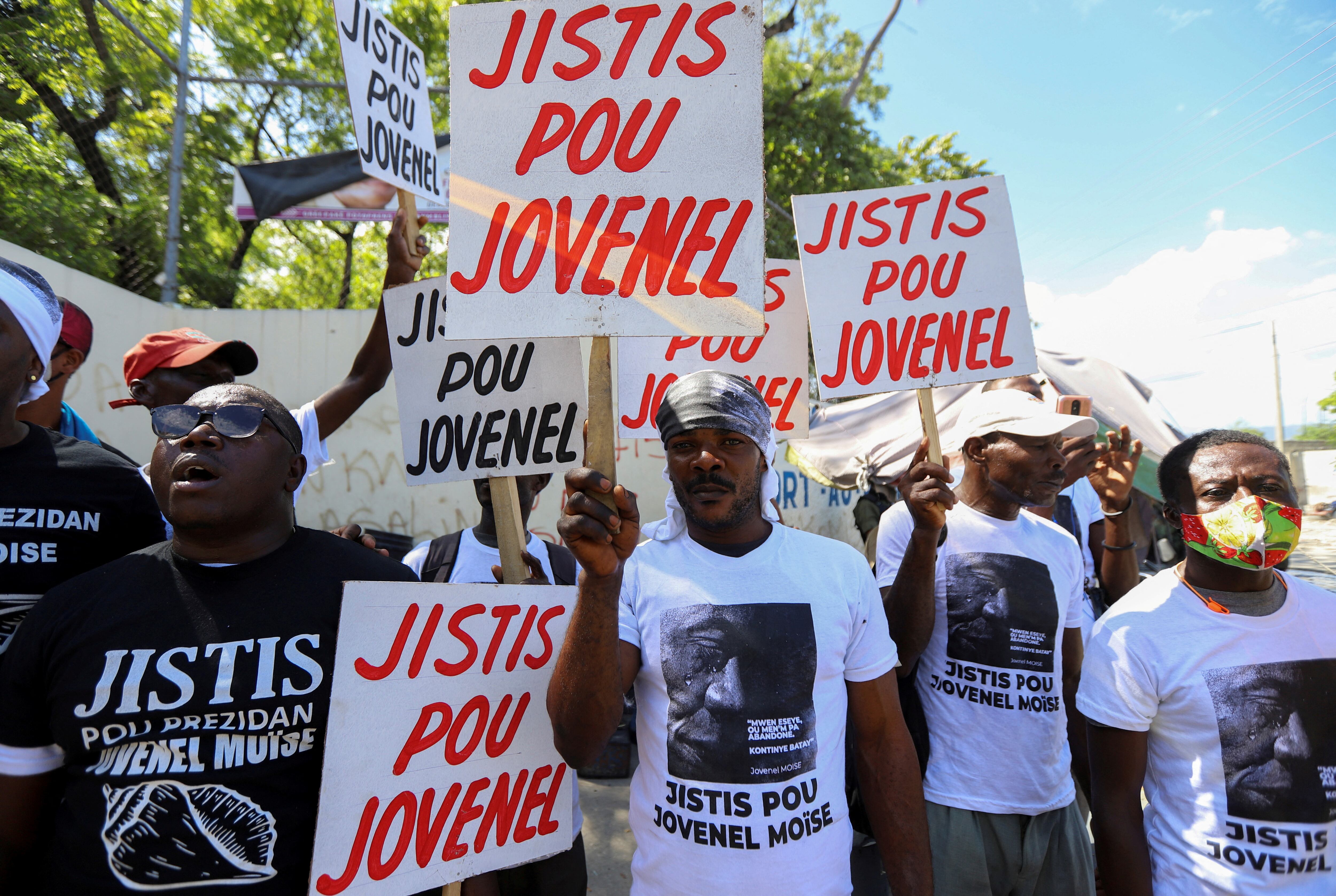 Demonstrators hold signs reading 'Justice for Jovenel' outside a judicial hearing into the assassination of President Jovenel Moise attended by former first lady Martine Moise, in Port-au-Prince, Haiti October 6, 2021.