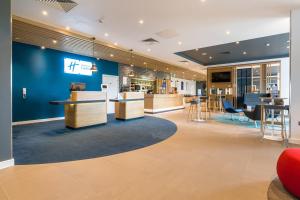 a lobby with a blue wall and tables and chairs at Holiday Inn Express - Bodmin - Victoria Junction, an IHG Hotel in Bodmin