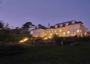 a large house with lights in a yard at night at The St Enodoc Hotel in Wadebridge