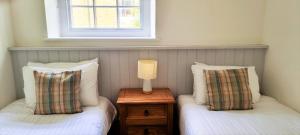 two twin beds in a room with a lamp on a table at Tregenna Castle Resort in St Ives