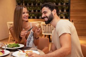 Een man en een vrouw die aan een tafel eten. bij Fujairah Rotana Resort & Spa - Al Aqah Beach in Al Aqah