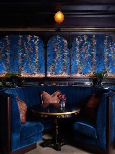 a dining room with blue walls and a table and chairs at NoMad London in London