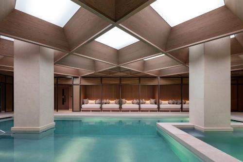 a pool in a building with a large ceiling at The Londoner in London