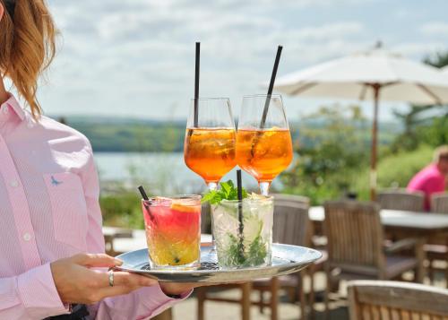 a woman holding a tray with three drinks on it at The St Enodoc Hotel in Wadebridge