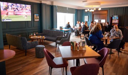 un grupo de personas sentadas en mesas en un restaurante en Thistle London Heathrow Terminal 5 en Hillingdon