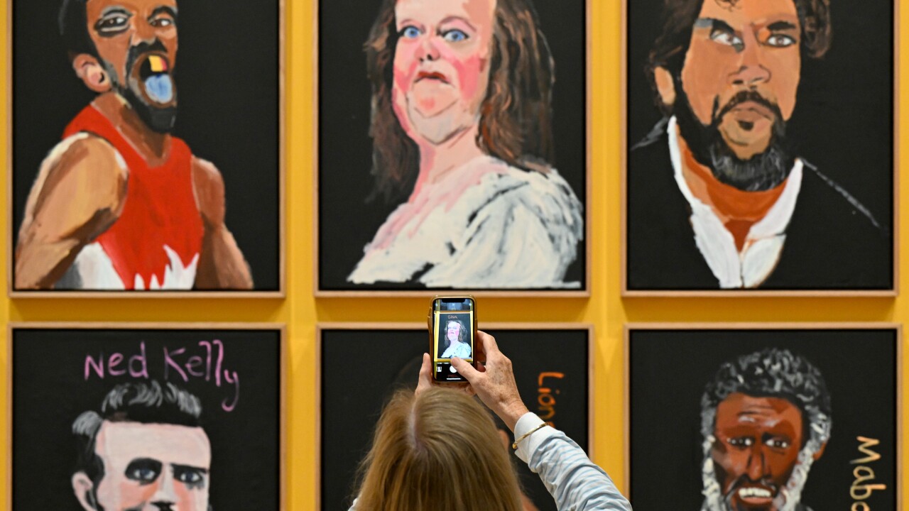 A woman taking a photo of the Gina Rinehart portrait in Vincent Namatjira's Australia in Colour work.