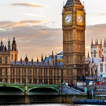 A large building with a clock tower and a bridge over a river. 