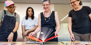 A group of four people standing around a table looking at pop-up books