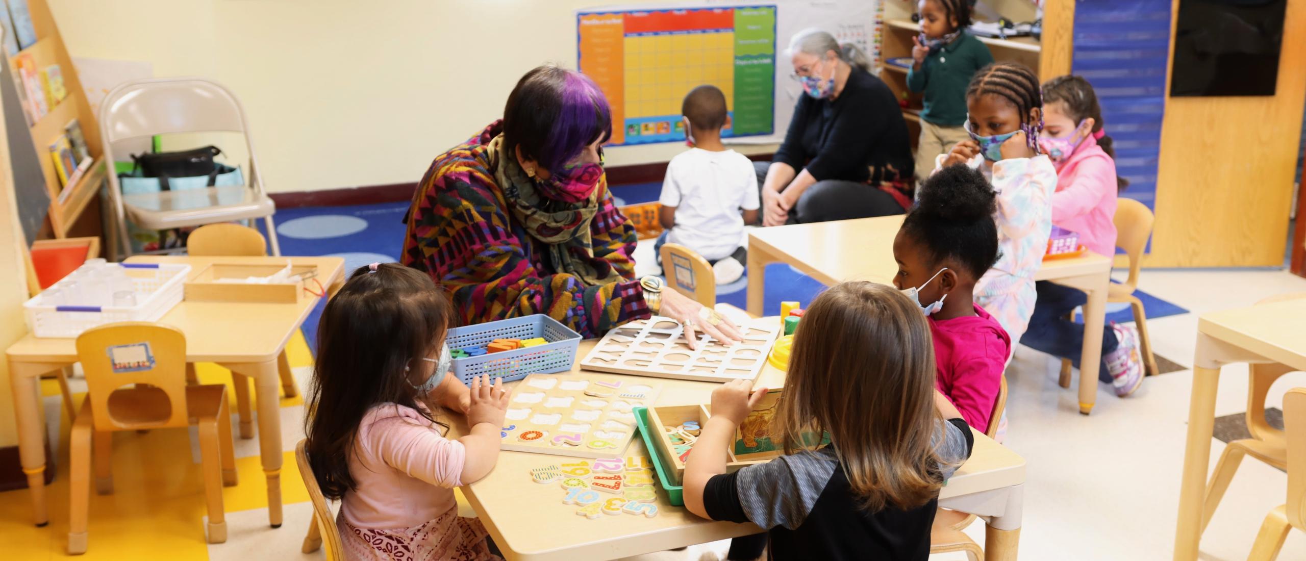 Rosa DeLauro sits at a table with young students