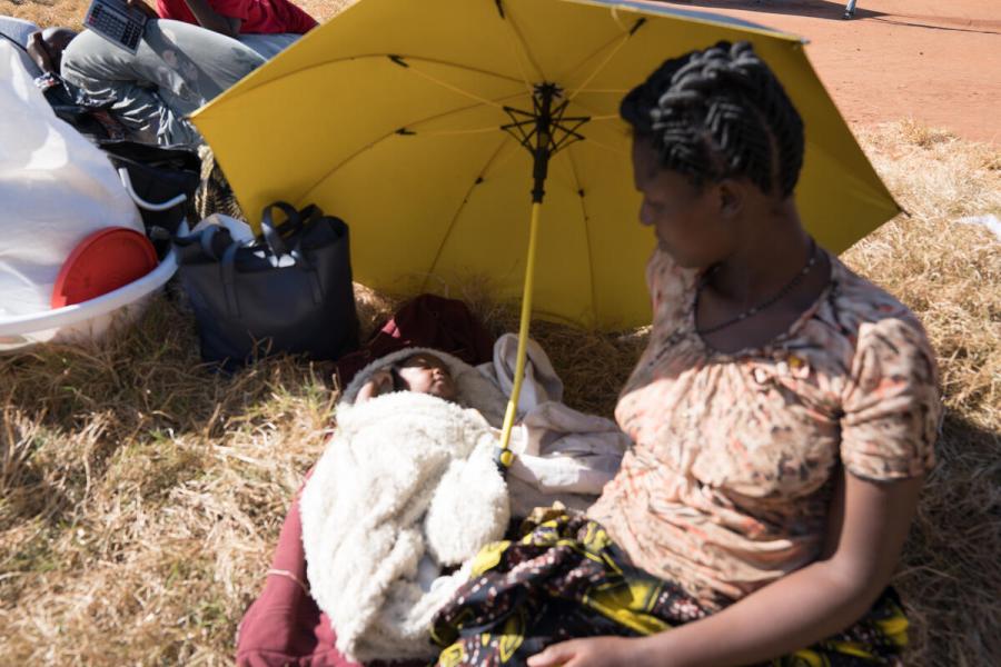 Woman looks at her child while holding and umbrella.