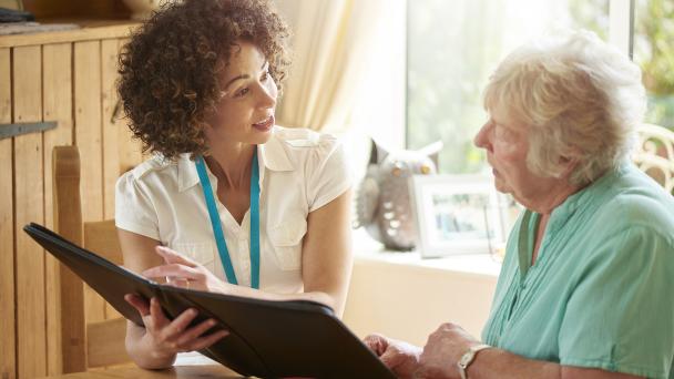 Carer or visiting nurse, speaks to an older woman.