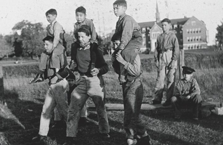 Group of students sitting, standing, and some sitting on the others shoulders.