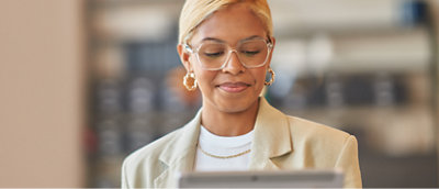 A woman wearing spectacles smiling and looking in a tablet