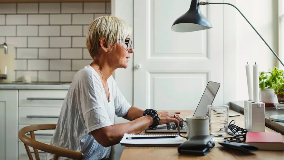 woman working on her laptop at a table in the kitchen