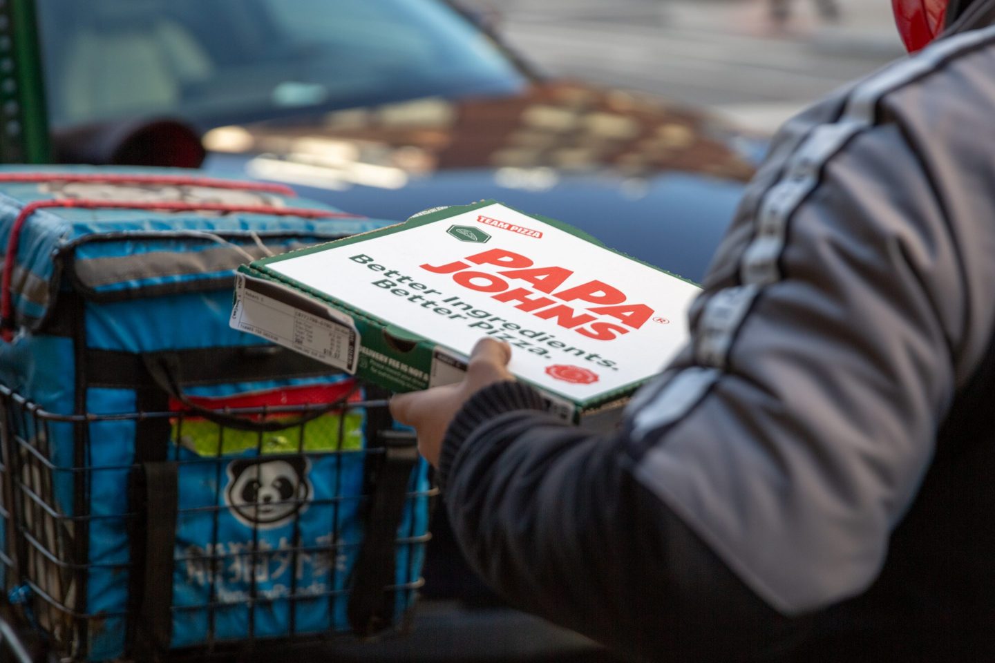 A delivery worker carries a Papa John's pizza outside a restaurant in New York City on Feb. 25, 2024.