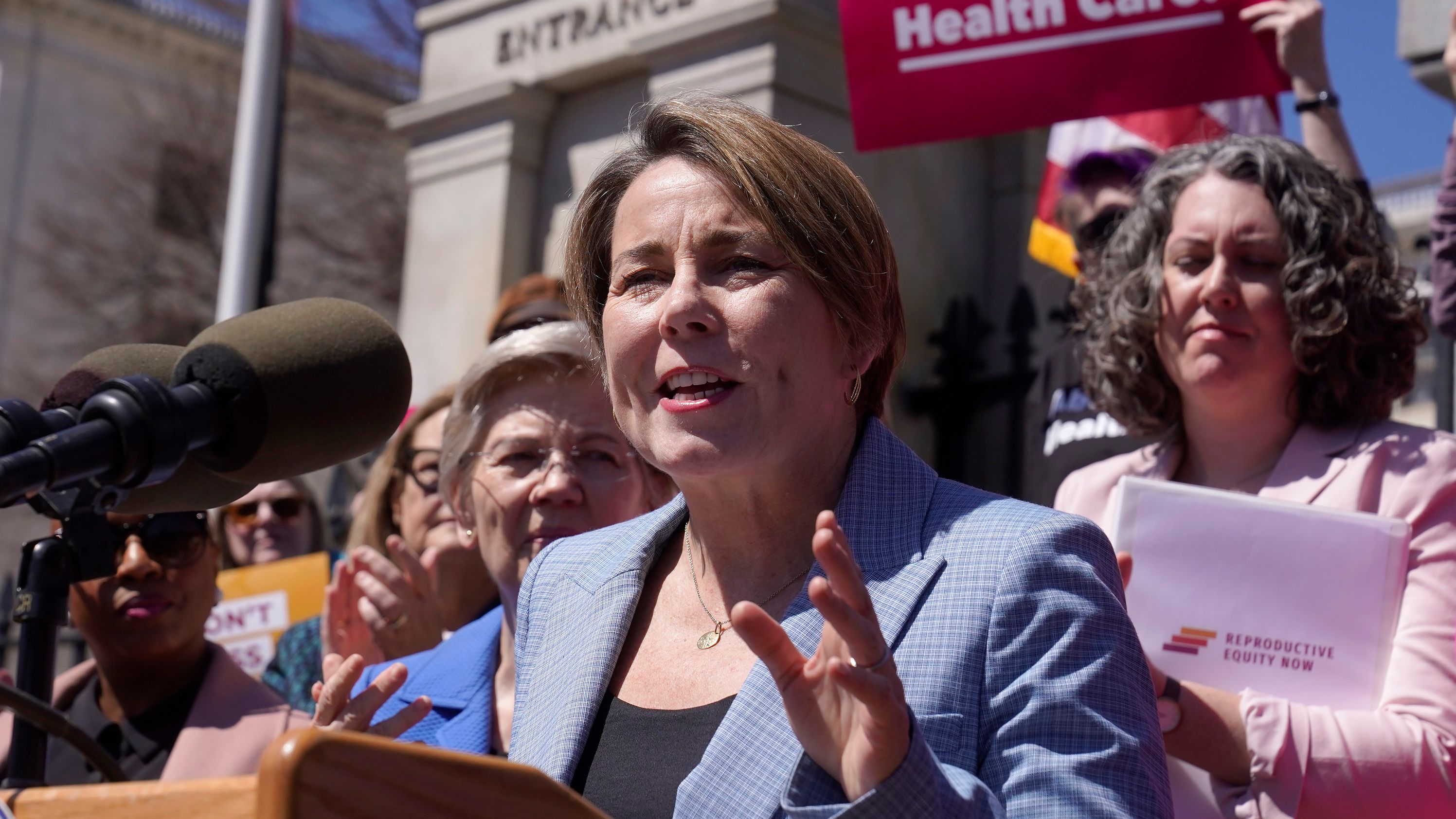 Massachusetts Democratic Gov. Maura Healey, front, faces reporters as U.S. Sen. Elizabeth Warren, D-Mass., behind center left, looks on, Monday, April 10, 2023, during a news conference in front of the Statehouse, in Boston. Massachusetts is stockpiling enough doses of mifepristone to last for more than a year Healey said Monday, April 10. (AP Photo/Steven Senne)