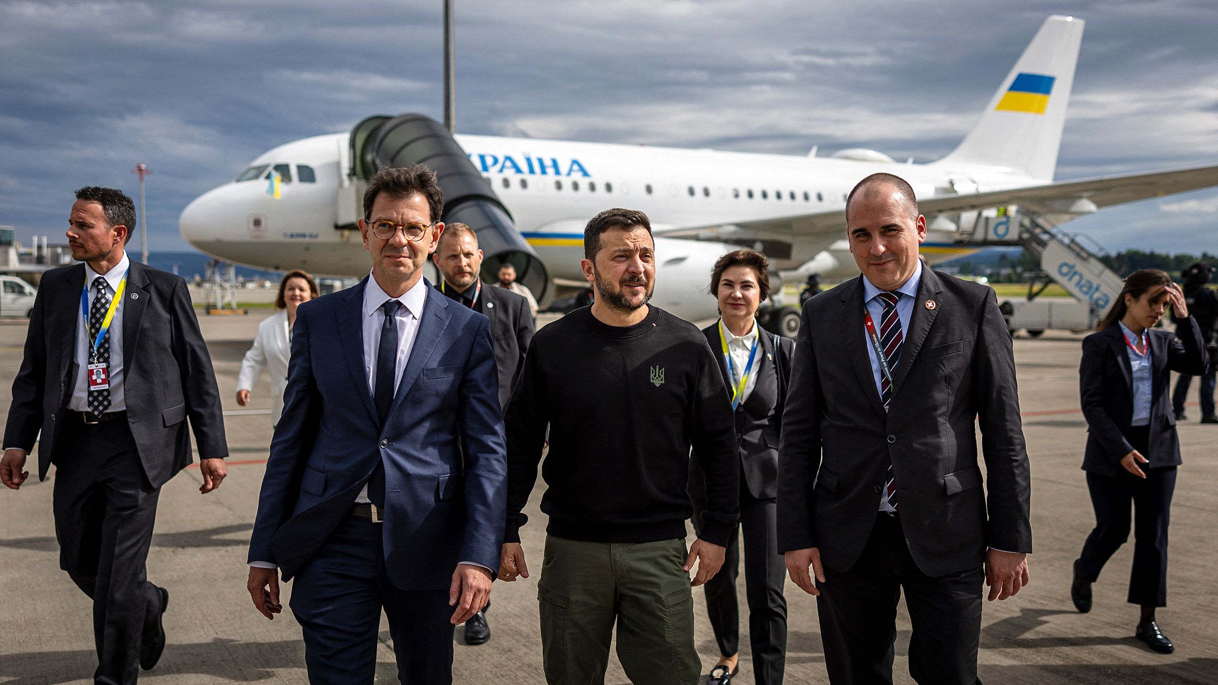 Ukraine's President Volodymyr Zelensky, center, is welcomed by Switzerland's Ambassador to Ukraine Felix Baumann, left, and Deputy Head of Swiss Protocol Manuel Irman, right, as he arrives at the Zurich airport on June 14, 2024, ahead of the Ukraine Peace Summit in Switzerland. World leaders from countries around the world will gather in the luxury Burgenstock resort, central Switzerland this weekend to try to work out a way towards a peace process for Ukraine — albeit without Russia.