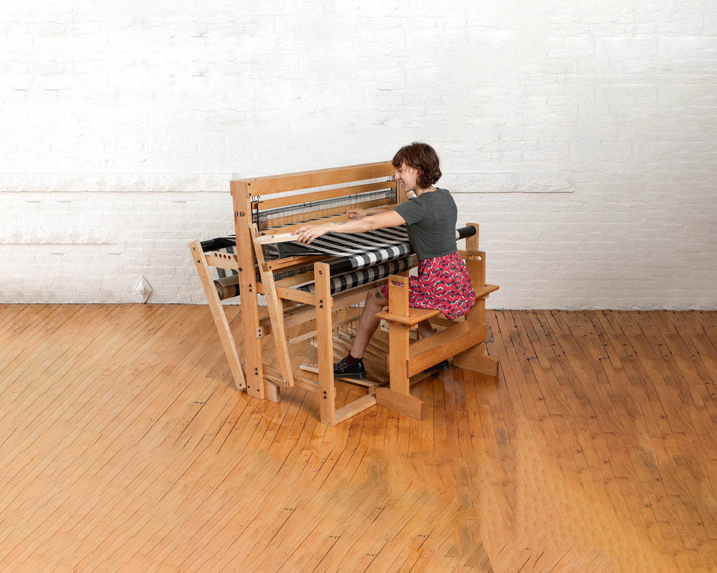 Woman weaving with a floor loom 