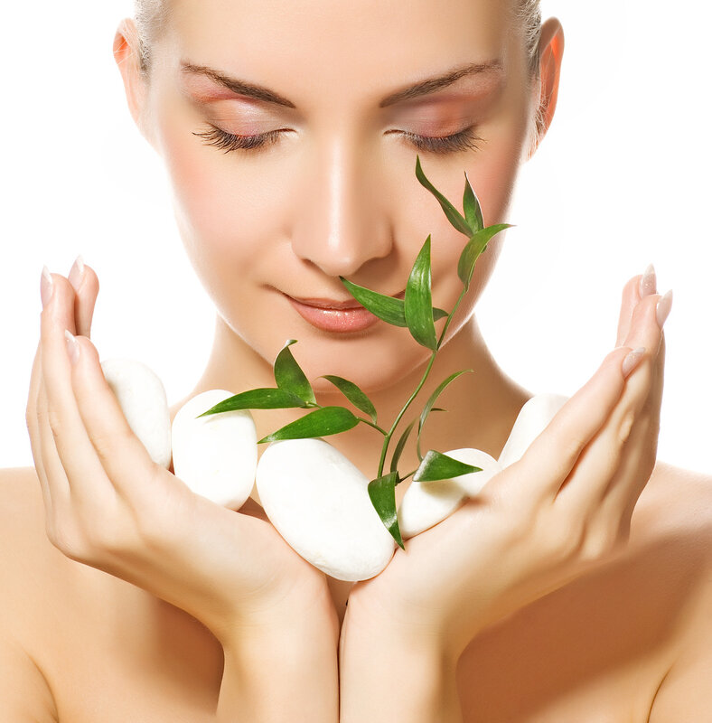 Beautiful young woman holding plant growing up through stones