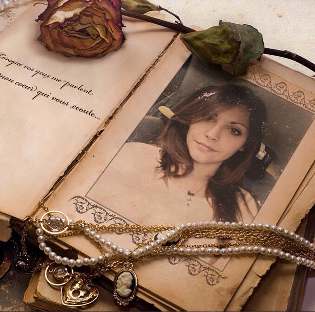 Photo of a young attractive girl put into a vintage photo frame with adornments: perl necklace, rose, paper, etc