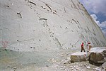 People inspecting dinosaur footprints on a steep wall