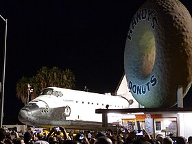 The Randy's Donuts sign alongside Space Shuttle Endeavour as it is ferried through the streets of Los Angeles on Friday, October 12, 2012.