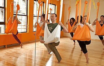 Aerial yoga class practising Flying Pigeon Pose, a hammock-supported variant[11]
