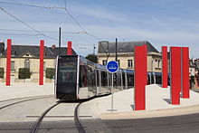 Une rame de tramway quittant la station Tranchée, passe entre les colonnes rouges de Daniel Buren.