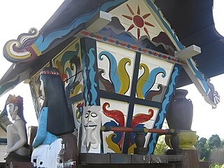 Bagian sisi Sandung yang berhiaskan lukisan matahari dan sepasang patung lelaki dan perempuan