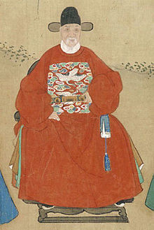 Malovaný portrét bělovousého sedícího muže v červeném rouchu a s černou čapkou.
