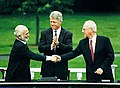 Una encaixada de mans entre el Rei Hussein i el Primer Ministre Rabbín, acompanyat pel President Clinton, durant les negociacions de pau entre Israel i Jordània, 25 de juliol de 1994