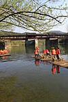 Berwisata menggunakan getek (rakit bambu) dekat Jembatan Pelangi Tsinghua