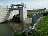 Comporta de guillotina i sobre-eixidor. El nivell del canal queda per sota del nivel màxim, definit pel sobre-eixidor.