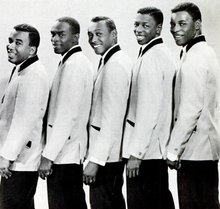 The Spinners standing together, dressed in matching suits