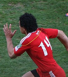 Vue de côté d'un joueur en train de courir, le bras gauche en avant, et la tête tournée vers le côté opposé à la prise de vue.