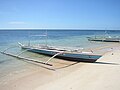 مركب جوكونج ذات أذرع امتداد مثبتة على شاطئ جزيرة ماناموك في الفلبين