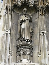 Photo de la statue d'un évêque mitré portant une image du Christ.