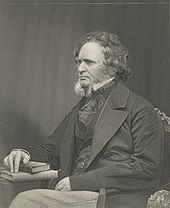 A stately-looking gentleman in a dark suit, sitting with a book