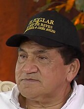 Close-up of a man with a white shirt and a black cap.