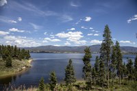 Lake with mountains in background and tall trees in foreground