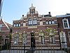 Rijk gedecoreerd woonhuis, liggend in straatwand met symmetrische gevelopbouw in neorenaissance stijl. Langskap. Opgaande middenpartij met steekkap.