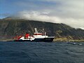 O navio alemão Maria S. Merian em Tristão da Cunha. Ao fundo pode ser visto o Queen Mary's Peak e à direita do navio está o povoado de Edimburgo dos Sete Mares.