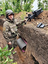 A Ukrainian soldier, equipped with an anti-drone gun, in a trench during the 2022 Russian invasion of Ukraine.