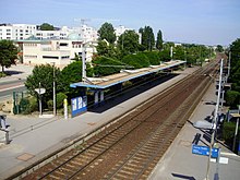 Vue aérienne de la gare de Chanteloup-les-Vignes, surplombée par des barres de HLM