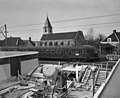 Bouw van Station Sloterdijk, met een juist passerend treinstel Mat '46. Op de achtergrond de Petruskerk; 3 april 1956.