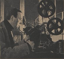 Homme penché sur un appareil pour modifier des films cinématographiques.